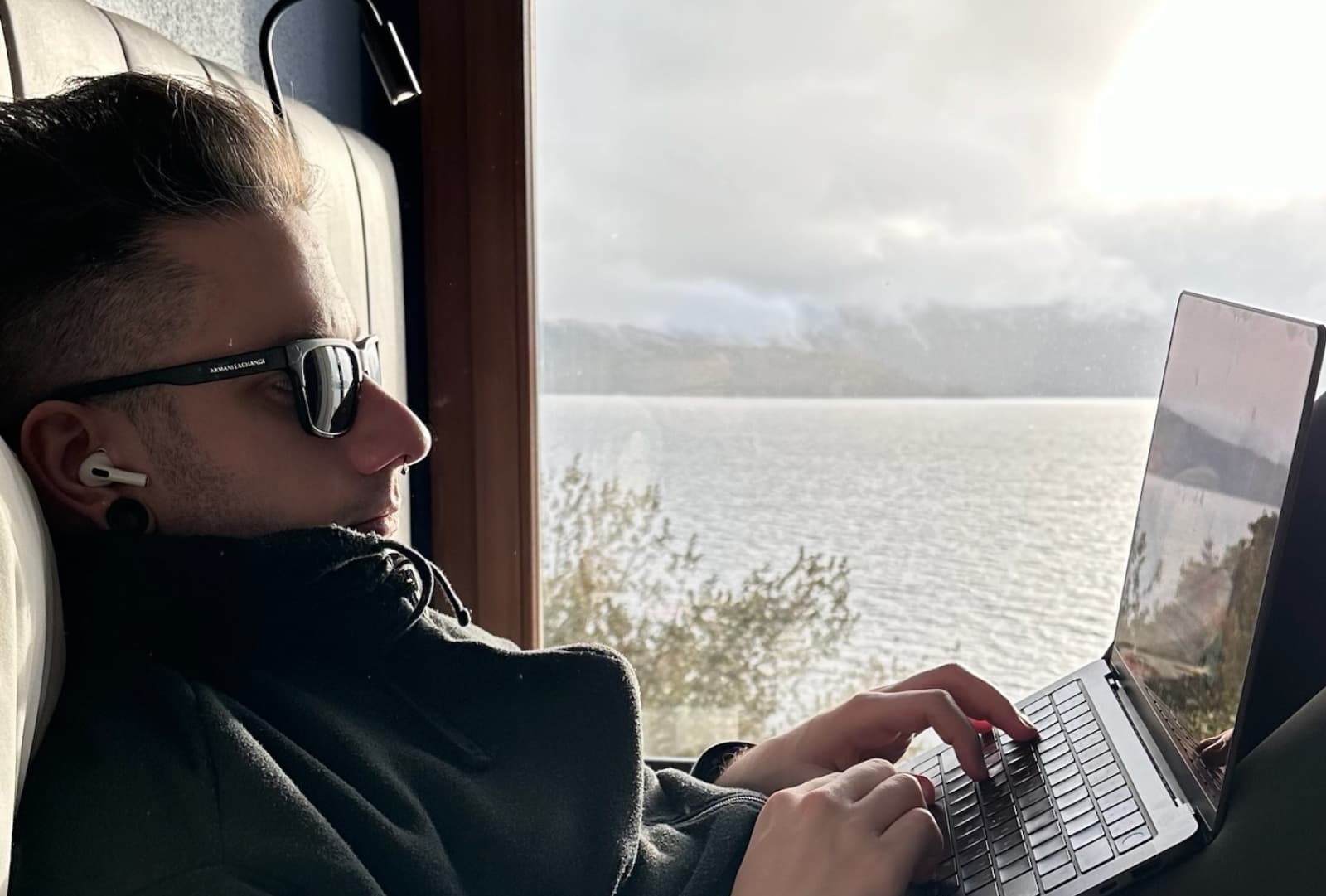 Picture of Gab, founder of Nootris, with its laptop coding on the bed with a lake view on the back